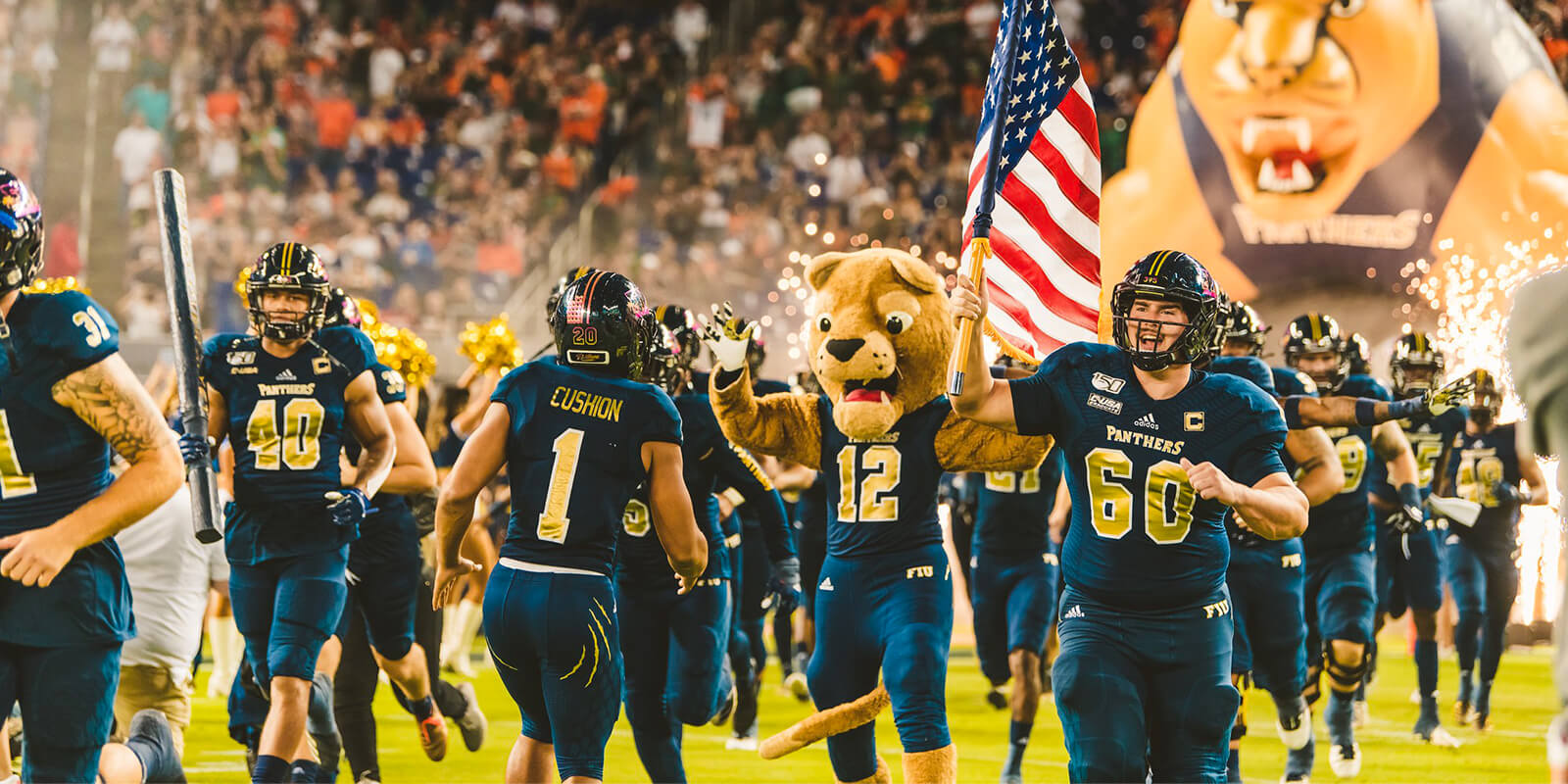 FIU football team running down the stadium holding an American flag prior to a match beginning. 