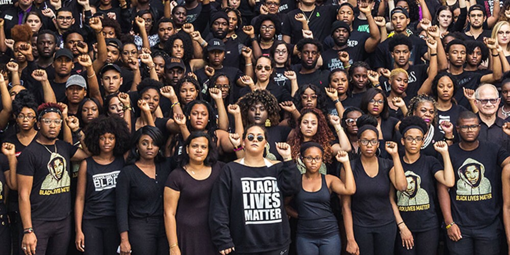 A congregation of black students with their fist held tight in the air.