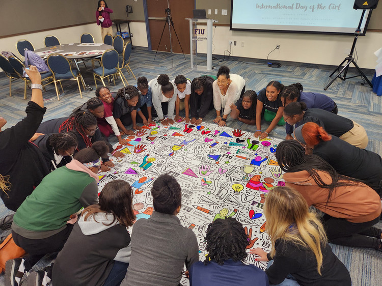 Students in a circle doing a craft on the floor