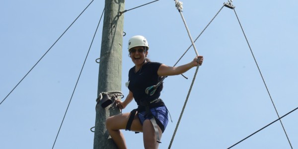 A student is fastened to a rope used to climb vertically against a surface. 